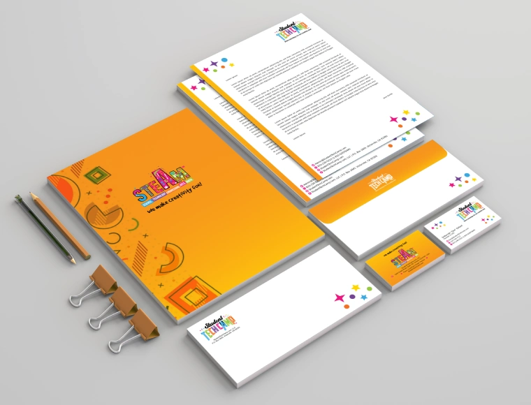 Custom logo design mockup for STEAM student camp stationery set featuring yellow-toned branding on notebook, pencil, backpack tag, and envelope with playful educational icons.