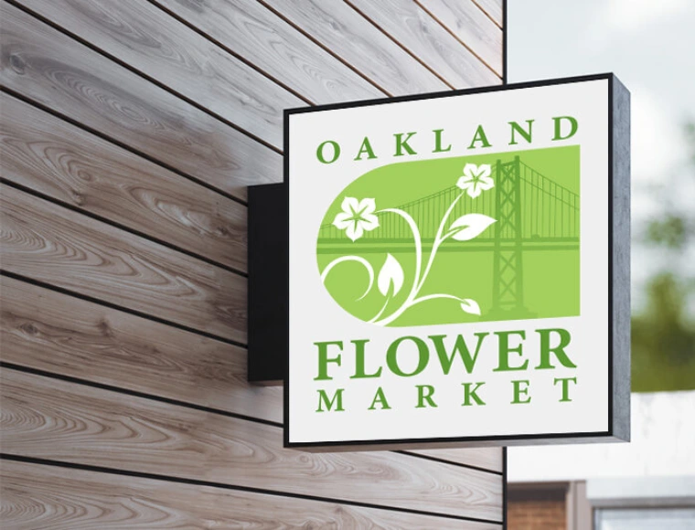 Custom logo design for Oakland Flower Market mounted on a storefront sign featuring floral-inspired typography and botanical iconography in soft natural colors.
